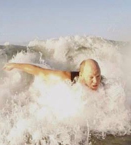 man bodysurfing through the foam